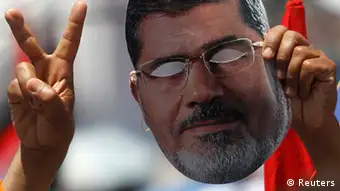 A member of the Muslim Brotherhood and supporter of ousted Egyptian President Mohamed Mursi holds up a mask of Mursi while gesturing during a rally around Rabaa Adawiya square, in Cairo July 26, 2013. The Egyptian army is detaining Mursi over accusations of kidnapping, killing soldiers and other charges, the state news agency said on Friday. REUTERS/Amr Abdallah Dalsh (EGYPT - Tags: POLITICS CIVIL UNREST)
