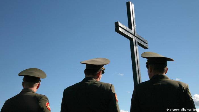 Российские военные стоят под крестом на кладбище
