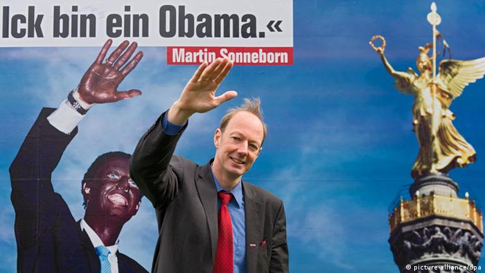 Martin Sonneborn, Bundesvorsitzender der PARTEI, posiert vor einem Wahlplakat (Foto: picture alliance/dpa)