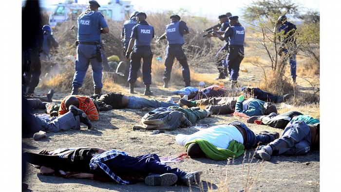 Police officers stand near several bodies lying on the ground