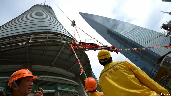 Construction workers watch as the final steel beam is hoisted to be put in place in a ceremony for the topping out of the Shanghai Tower in Shanghai on August 3, 2013. Work on the main structure of the world's second tallest skyscraper was completed as a crane placed the steel beam 580 meters (1,900 feet) above the ground as the building formally overtook Taiwan's 509 meter tall Taipei 101 building to become the tallest tower in Asia. AFP PHOTO/Peter PARKS (Photo credit should read PETER PARKS/AFP/Getty Images)