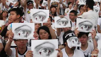 People, holding placards of a bleeding eye, take part in a demonstration in front of the Presidential Office in Taipei August 3, 2013. Hundreds of thousands of demonstrators gathered on Saturday to mourn for soldier Hung Chung-chiu, who died of severe heatstroke after being ordered to do strenuous exercises in a barracks on July 4, and to demand further investigation into Hung's case, according to event organizers. REUTERS/Steven Chen (TAIWAN - Tags: POLITICS MILITARY CIVIL UNREST)