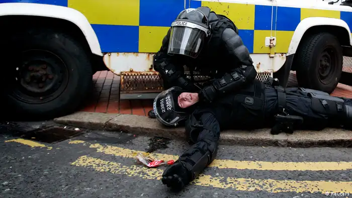 A police officer is tended to by a colleague after Loyalist protesters attacked the police with bricks and bottles as they waited for a republican parade to make its way through Belfast City Centre, August 9, 2013. Police fired plastic bullets and water cannon at rioters in the heart of Belfast on Friday after being pelted by missiles for the second successive night in the latest bout of Northern Ireland's sporadic sectarian violence. Police said two officers were injured. Eight were hurt the previous night when a crowd threw paint bombs, bottles and masonry at police. REUTERS/Cathal McNaughton (NORTHERN IRELAND - Tags: CIVIL UNREST CRIME LAW TPX IMAGES OF THE DAY)