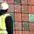 Ein Mitarbeiter der Hamburger Hafen und Logistik AG (HHLA) steht am 05.03.2010 am Kai des Container Terminals Altenwerder im Hamburger Hafen vor einem riesigen Containerschiff. (Foto: dpa)