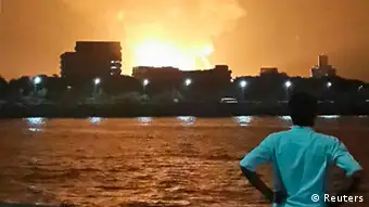 A man watches Indian Navy submarine INS Sindhurakshak on fire in Mumbai late August 13, 2013. An explosion on the Indian submarine on Wednesday killed crew members, India's defence minister said, giving no further details of what he described as one of the greatest tragedies of recent times. Picture taken late August 13, 2013. REUTERS/Vikalp Shah (INDIA - Tags: DISASTER MILITARY TPX IMAGES OF THE DAY)