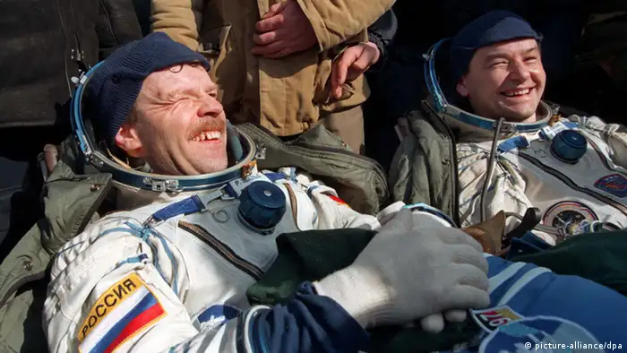 Von den Sonnenstrahlen geblendet werden der deutsche Astronaut Reinhold Ewald (l) und sein russischer Kollege Waleri Korsun (r), als sie am 2.3.1997 nach der geglückten Landung von Sojus TM-24 in der Steppe von Kasachstan neben ihrer Raumkapsel sitzen. Ewald hatte 20 Tage auf der russischen Raumstation Mir verbracht. Zu Ewalds Programm an Bord der Mir hatten medizinische Experimente, unter anderen Blutproben, Untersuchungen der Wirbelsäule sowie physische und psychologische Tests gehört. Außerdem war im Auftrag der Universität Halle ein Experiment zur Züchtung von Halbleiterkristallen unter den Bedingungen der Schwerelosigkeit geplant.