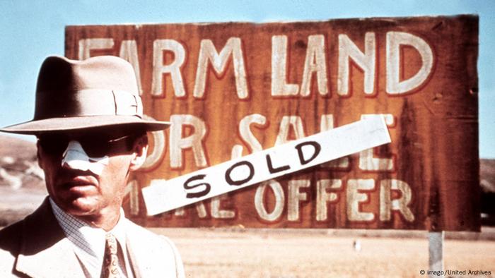 Jack Nicholson steht mit Hut, Sonnenbrille und verbundener Nase vor einem Schild mit der Aufschrift Farm Land For Sale - Sold in Polanskis Chinatown. (Film: Chinatown) (imago/United Archives)