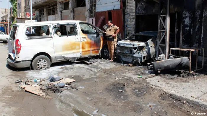 A man stands near vehicles damaged by the impact of a car bomb attack in Baghdad August 15, 2013. A series of car bombs in Baghdad killed at least 28 people and wounded more than 100 on Thursday, with one exploding near the Green Zone diplomatic complex, the latest attacks in some of the worst violence since U.S. troops left. REUTERS/Ahmed Saad (IRAQ - Tags: POLITICS CONFLICT)