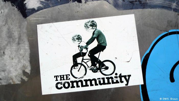 Sticker showing two stick figures on a bicycle and the words The Community
