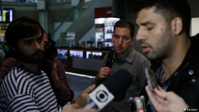 U.S. journalist Glenn Greenwald (C) looks on as his partner David Miranda (R) talks with the media after arriving at Rio de Janeiro's International Airport August 19, 2013. British authorities used anti-terrorism powers on Sunday to detain Miranda, the partner of Greenwald, who has close links to Edward Snowden, the former U.S. spy agency contractor who has been granted asylum by Russia, as he passed through London's Heathrow airport. The 28-year-old Miranda, a Brazilian citizen and partner of Greenwald who writes for Britain's Guardian newspaper, was questioned for nine hours before being released without charge, a report on the Guardian website said.. REUTERS/Ricardo Moraes (BRAZIL - Tags: POLITICS CRIME LAW MEDIA)