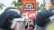 Ein NPD-Sympathisant protestiert am 20.08.2013 hinter einer Polizeikette mit einem Plakat der NPD gegen das neue Flüchtlingswohnheim in Berlin-Hellersdorf. Erneut sind Gegner und Befürworter des Heimes in auf die Straße gegangen. Foto: Ole Spata/dpa Ein NPD-Sympathisant protestiert am 20.08.2013 hinter einer Polizeikette mit einem Plakat der NPD gegen das neue Flüchtlingswohnheim in Berlin-Hellersdorf. Erneut sind Gegner und Befürworter des Heimes in auf die Straße gegangen. Foto: Ole Spata/dpa