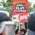 Ein NPD-Sympathisant protestiert am 20.08.2013 hinter einer Polizeikette mit einem Plakat der NPD gegen das neue Flüchtlingswohnheim in Berlin-Hellersdorf. Erneut sind Gegner und Befürworter des Heimes in auf die Straße gegangen. Foto: Ole Spata/dpa