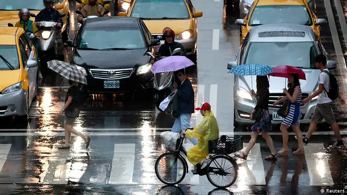 People holding umbrellas walk in the rain as tropical storm Trami approaches Taiwan, in Taipei August 20, 2013. REUTERS/Pichi Chuang (TAIWAN - Tags: ENVIRONMENT)