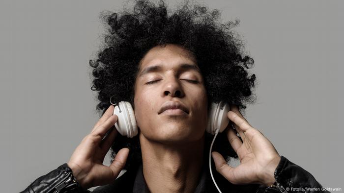 Homme avec afro écoutant de la musique au casque avec les yeux fermés