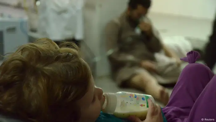A girl feeding from a bottle, as a man affected by what activists say was a gas attack breathes through oxygen mask, at a medical center in the Damascus suburbs of Saqba, August 21, 2013. Syria's opposition accused government forces of gassing hundreds of people on Wednesday by firing rockets that released deadly fumes over rebel-held Damascus suburbs, killing men, women and children as they slept. REUTERS/Bassam Khabieh (SYRIA - Tags: POLITICS CIVIL UNREST CONFLICT HEALTH)