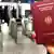 Женская рука с немецким паспортом на фоне стоек таможенного контроля в аэропорту