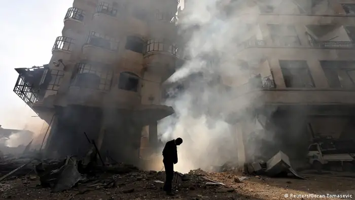 A man walks in front of a burning building after a Syrian Air force air strike in Ain Tarma neighbourhood of Damascus in this January 27, 2013 file photograph. The civil war that has unfolded in Syria over the past two and a half years has killed more than 100,000 people and driven millions from their homes. Now, in the wake of last week's chemical weapons attack near Damascus, the world is waiting to see what action Western powers will take and what impact this will have on the Middle Eastern nation and the rest of the volatile region. REUTERS/Goran Tomasevic/Files (SYRIA - Tags: CONFLICT CIVIL UNREST POLITICS TPX IMAGES OF THE DAY) ATTENTION EDITORS: PICTURE 28 OF 40 FOR PACKAGE 'SYRIA - A DESCENT INTO CHAOS.' SEARCH 'SYRIA TIMELINE' FOR ALL IMAGES