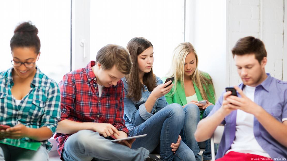 Jovens estudantes voltados para as telas de seus celulares