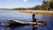An Aborigine paddles a canoe on a river in Australia An Aborigine paddles a canoe on a river in Australia