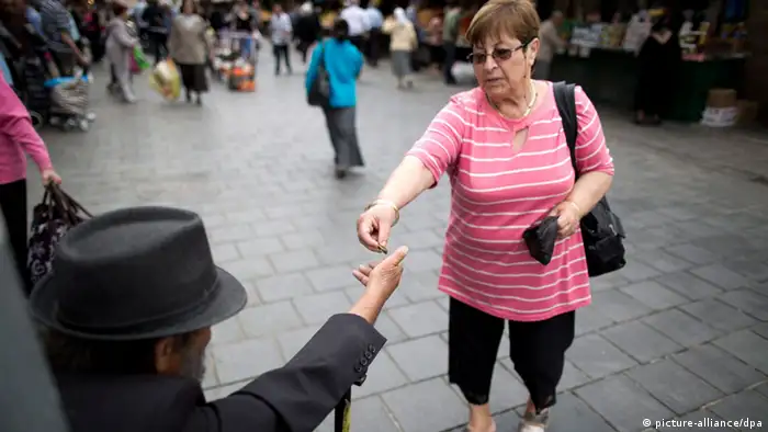 Eine Frau gibt in Jerusalem auf der Straße einem Bettler Geld.
Foto: EPA/ABIR SULTAN

