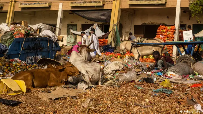 A boy sits in rubbish along the side of a road