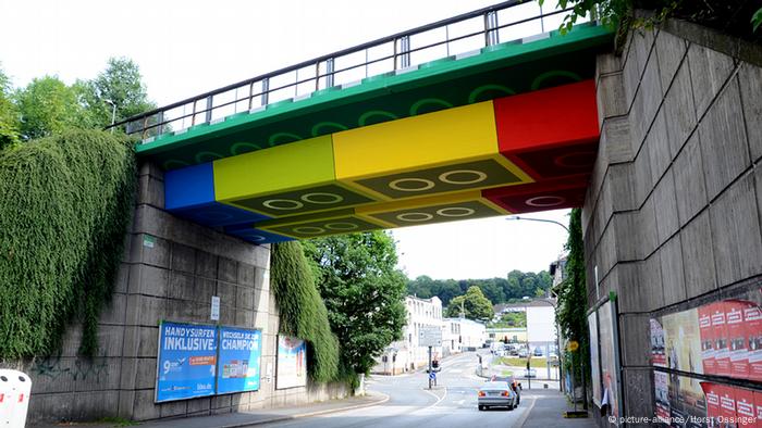 A cement railway bridge painted with a lego brick design. 