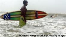 TO GO WITH AFP STORY Lifestyle-Bangladesh-surfing,FEATURE by Julie Clothier Bangladeshi surfer Jafar Alam prepares to surf in the waters of The Bay of Bengal at Cox's Bazar on June 30, 2008. With his fluorescent board shorts and muscular body, Jafar Alam does not look like a typical Bangladeshi. While most men his age in this conservative Muslim country are obsessed with cricket, the 25-year-old is more likely to be found surfing the waves on one of the worldï¿½s longest beaches. Alam, who says he is Bangladeshï¿½s first surfer, is working to not only popularise the sport, but also to build international recognition for the largely untouched beach where he surfs. AFP PHOTO/Farjana Khan GODHULY (Photo credit should read Farjana KHAN GODHULY/AFP/Getty Images)