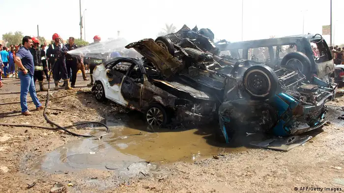 A picture taken on September 15, 2013 shows Iraqis and firefighters gathering near burnt vehicles at the scene of a car bomb explosion in Nasiriyah, south of the Iraqi capital Baghdad. A wave of attacks across Iraq, the deadliest of which struck south of Baghdad, killed 26 people and left dozens more wounded, security and medical officials said. AFP PHOTO STR (Photo credit should read -/AFP/Getty Images)