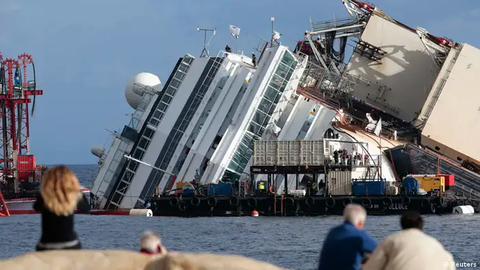 People look on as the capsized cruise liner Costa Concordia lies on its side next to Giglio Island September 16, 2013. Salvage engineers pushed back the start of an operation on Monday to lift the wrecked liner upright after an overnight storm interrupted preparations, officials said. The a so-called parbuckling operation will see the ship rotated by a series of cranes and hydraulic machines, pulling the hulk from above and below and slowly twisting it upright. REUTERS/Tony Gentile (ITALY - Tags: DISASTER MARITIME SOCIETY)