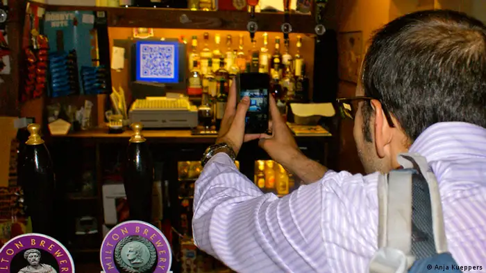Bitcoin QR code on till as customer uses scanner app to quickly pay in Bitcoins. London, Pembury Tavern, August 2013
