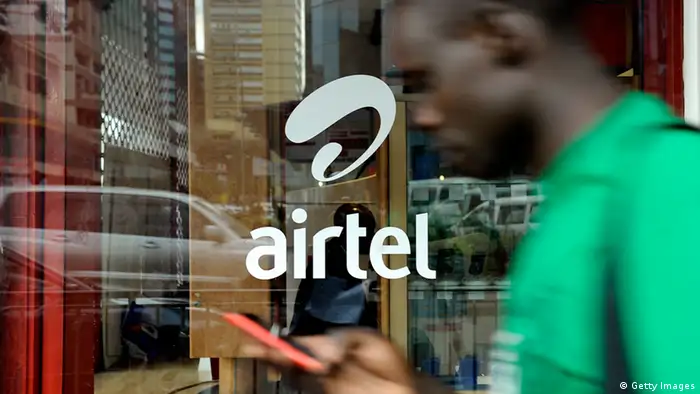 A man with his phone in hand walks past a window branded in an 'Airtel' logo.