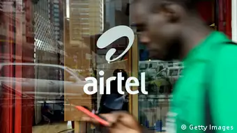 A man with his phone in hand walks past a window branded in an 'Airtel' logo in the Kenyan capital, Nairobi.