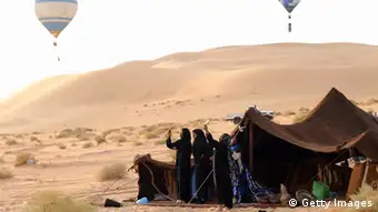 A group of people in the desert hold cellphones