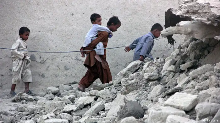 Survivors of an earthquake walk on rubble of a mud house after it collapsed following the quake in the town of Awaran, southwestern Pakistani province of Baluchistan, September 25, 2013. The death toll from a powerful earthquake in Pakistan rose to at least 208 on Wednesday after hundreds of mud houses collapsed on people in a remote area near the Iranian border, officials said. REUTERS/Sallah Jan (PAKISTAN - Tags: DISASTER)