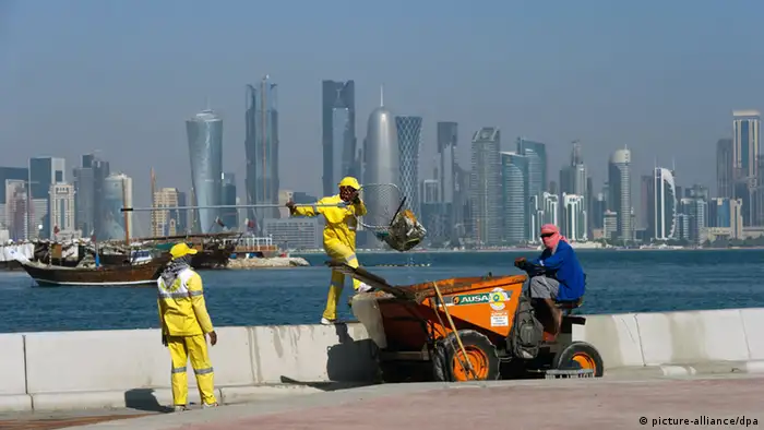 Drei Arbeiter fischen vor der Skyline von Doha Müll aus dem Meer, aufgenommen am 25.11.2010. Foto: Arno Burgi