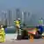 Drei Arbeiter fischen vor der Skyline von Doha Müll aus dem Meer (Foto: picture-alliance/dpa)