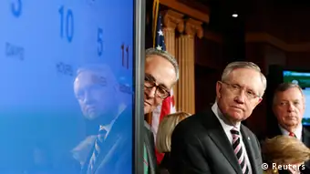 U.S. Senate Majority Leader Harry Reid (D-NV) (3rd R) looks at a screen showing a clock counting down to a government shutdown, at a news conference with fellow Democrats Senator Chuck Schumer (D-NY) (4th R), Senator Barbara Mikulski (D-MD) (2nd R) and Senator Dick Durbin (D-IL) (R) after the Senate voted to pass a spending bill in an attempt to avoid the shutdown, sending the issue back to the House of Representatives, at the U.S. Capitol in Washington September 27, 2013. The U.S. government braced on Friday for the possibility of a partial shutdown of operations on October 1 as Congress struggled to pass an emergency spending bill that Republicans want to use to defund the new healthcare reform law. REUTERS/Jonathan Ernst (UNITED STATES - Tags: POLITICS BUSINESS TPX IMAGES OF THE DAY)