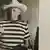 Pablo Picasso steht mit Zigarette und Waffe in einer Tür, hinter ihm hängt ein Bild, das ihn in derselben Pose zeigt (Foto: DW TV PICASSO Bild02)