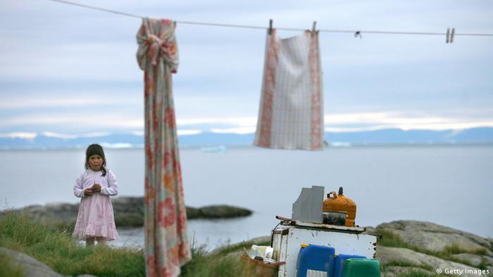 an Inuit girl stands in her backyard in the village of Ilimanaq, Greenland