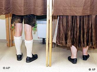 A couple in traditional Bavarian costume stand in polling booths