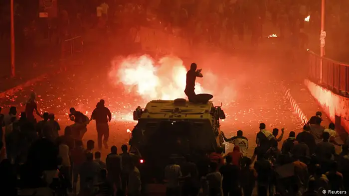 A riot police officer, on a armoured personnel carrier surrounded by anti-Mursi protesters (foreground), fires rubber bullets at members of the Muslim Brotherhood and supporters of ousted Egyptian President Mohamed Mursi along a road at Ramsis square, which leads to Tahrir Square, during clashes at a celebration marking Egypt's 1973 war with Israel, in Cairo October 6, 2013. At least 28 people were killed and more than 90 wounded in clashes during protests in Egypt on Sunday, security sources and state media said, as the crisis since the army seized power three months ago showed no sign of abating. REUTERS/Amr Abdallah Dalsh (EGYPT - Tags: POLITICS CIVIL UNREST)