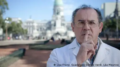 Argentine surgeon German Cardoso in front of the congress building in Buenos Aires. He is pressing his index finger to his lips in a gesture of silence. (Copyright: Lisa Franz, Guadalupe Gómez Verdi, Léa Meurice)