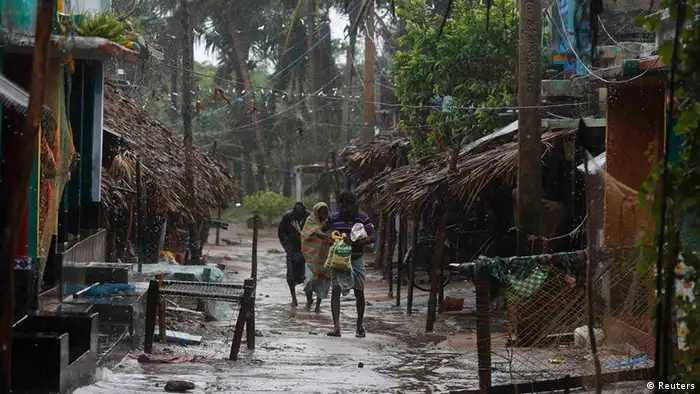 A family carries their belongings as they move to a safer place at the village of Donkuru in Srikakulam district, in the southern Indian state of Andhra Pradesh October 12, 2013. Rain and wind lashed India's east coast on Saturday, forcing more than 400,000 people to flee to storm shelters as one of the country's largest cyclones closed in, threatening to cut a wide swathe of devastation through farmland and fishing hamlets. Filling most of the Bay of Bengal, Cyclone Phailin was about 200 km (124 miles) offshore by noon on Saturday, satellite images showed, and was expected to hit land by nightfall. REUTERS/Adnan Abidi (INDIA - Tags: ENVIRONMENT DISASTER)
