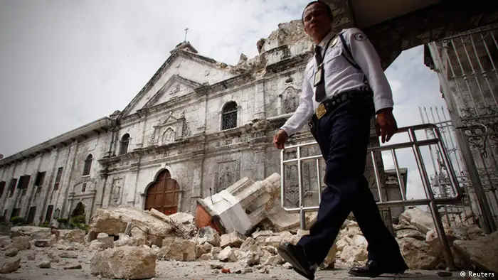 A security guard walks past the bell tower church of historic Basilica Minore of Sto Nino that fell down after an earthquake hit Cebu city, central Philippines October 15, 2013. City. At least six people were killed when buildings collapsed on islands popular with tourists in the central Philippines on Tuesday, radio reports said, after an earthquake measuring 7.2 hit the region. REUTERS/Stringer (PHILIPPINES - Tags: DISASTER ENVIRONMENT RELIGION)