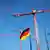 ARCHIV - Die europäische und die deutsche Flagge ist am 12.10.2012 im Regierungsviertel in Berlin zwischen Baukränen zu sehen. Die deutsche Wirtschaft verliert in der Schuldenkrise zunächst an Fahrt, der Arbeitsmarkt bleibt aber voraussichtlich trotzdem stabil. Foto: Wolfgang Kumm/dpa +++(c) dpa - Bildfunk+++