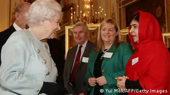 Queen Elizabeth II speaks to Malala Yousafzai (R) during a Reception for Youth, Education and the Commonwealth at Buckingham Palace in London on October 18, 2013. The 16-year-old, who was shot by the Taliban for championing girls' rights to an education, met Queen Elizabeth at a reception for youth, education and the Commonwealth. AFP PHOTO/POOL/Yui Mok (Photo credit should read YUI MOK/AFP/Getty Images)