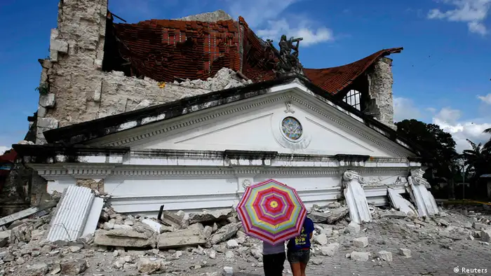 Residents look at a collapsed Holy Trinity parish church at Loay, Bohol after an earthquake struck central Philippines October 17, 2013. The Philippines started to clear roads blocked by debris on Thursday as it reckoned up the cost of this week's powerful earthquake, with the death toll rising to at least 158. Tens of thousands of residents of Bohol island, which took the brunt of Tuesday's 7.2 magnitude quake, remained living outdoors, for fear of aftershocks bringing down damaged homes. REUTERS/Erik De Castro (PHILIPPINES - Tags: DISASTER TPX IMAGES OF THE DAY RELIGION)