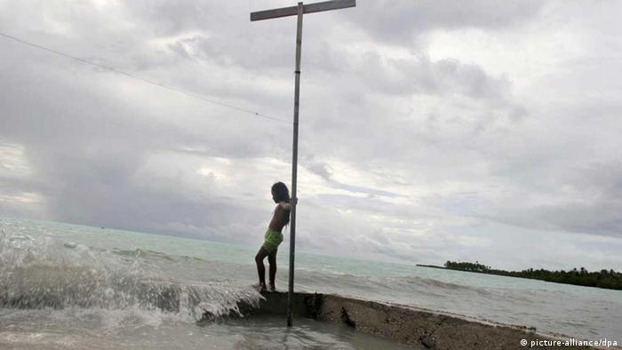 A young girl on the South Pacific island of Kiribati, watches the sea water during a king tide wash over a wall built by her family to protect their land from erosion by the encroaching sea. (Photo: EPA/Jeremy Sutton-Hibbert)