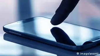 A fingertip and its reflection on the screen of a mobile phone
