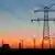 Strommast bei Sonnenuntergang mit Windrädern und Kernkraftwerk (Foto: Fotolia/Thorsten Schier)